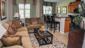 A living room with a sofa, coffee table, and a dining area with chairs and a table.