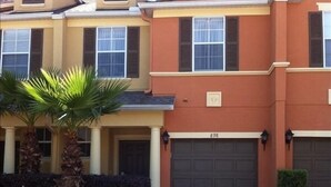 A two-story house with a garage, palm trees, and a well-maintained lawn.