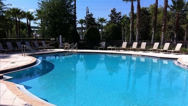 A clear blue pool with lounge chairs and palm trees in the background.