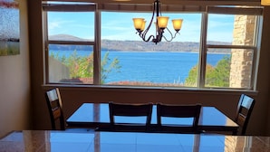 Una cocina con un amplio ventanal con vistas a un lago, una araña y una encimera de granito.