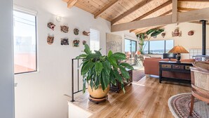 Een ruime woonkamer met houten vloeren, een grote potplant, een bank, een salontafel en een televisie.