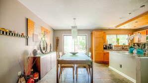 Eine geräumige Küche mit einer zentralen Kochinsel, Holzschränken und einem großen Fenster für natürliches Licht.