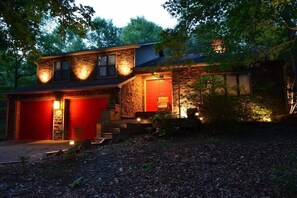 A two-story house with a stone facade, red garage doors, and exterior lighting. - Urban Escape w/Hot Tub, Backyard Oasis, Min to Uptown! (Charlotte)