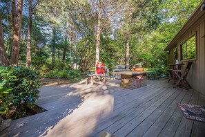 An outdoor deck with a barbecue area, surrounded by tall trees and a wooden building. - Urban Escape w/Hot Tub, Backyard Oasis, Min to Uptown! (Charlotte)