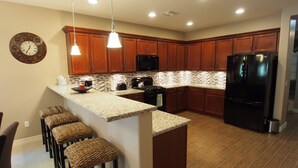 Una cucina moderna con mobili in legno, piani in granito e un frigorifero nero.