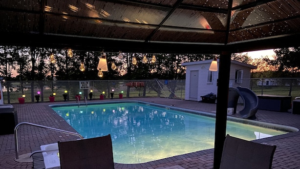 Una piscina con un porche techado, sillas de descanso y un tobogán.