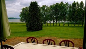 Una mesa de comedor con sillas y vistas a un área verde con árboles y una masa de agua.