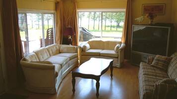 Una sala de estar con un sofá, sillones, una mesa de centro y un televisor.