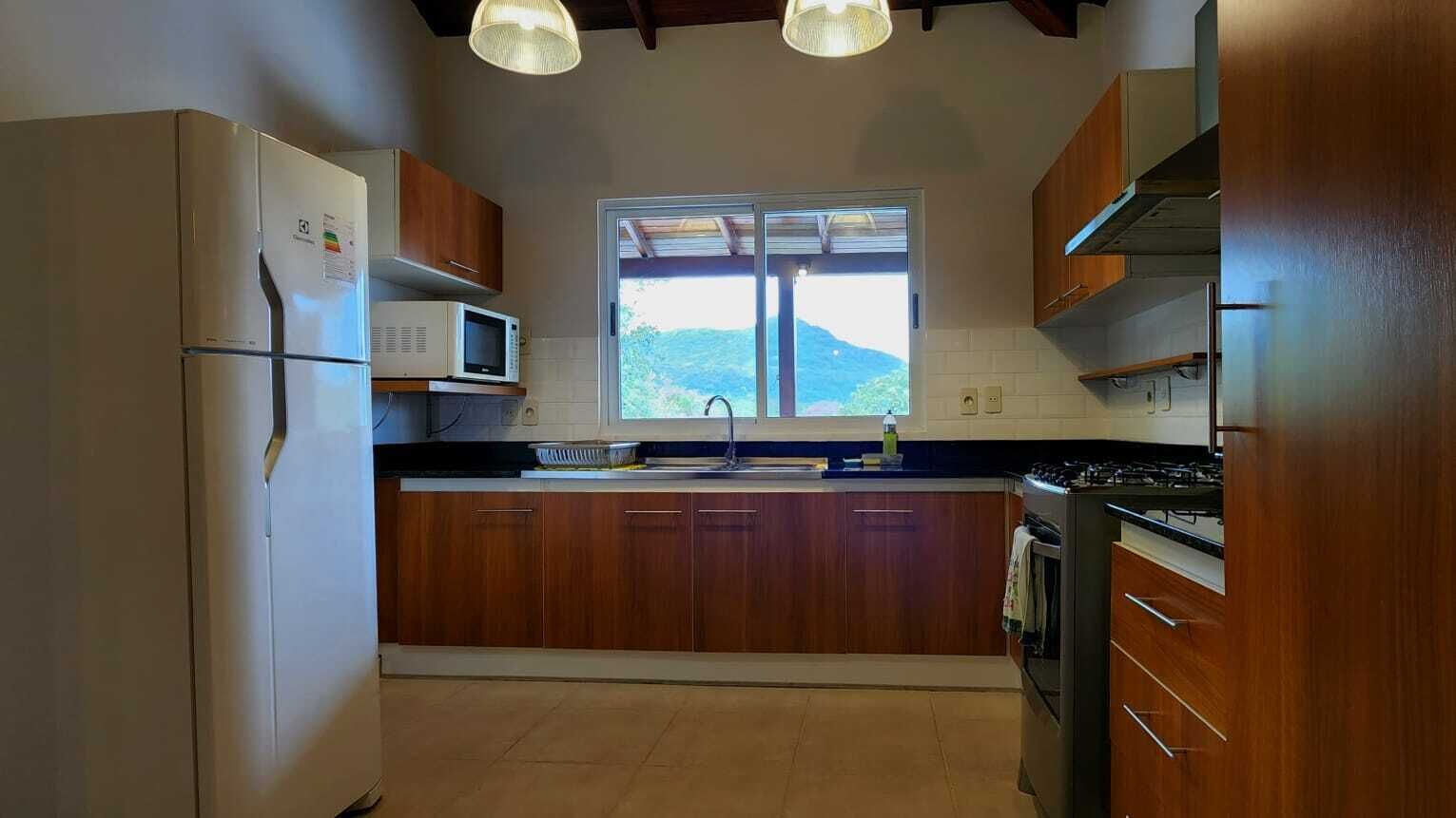Une cuisine avec des meubles en bois, un réfrigérateur blanc, un four à micro-ondes, une cuisinière et une fenêtre donnant sur l’extérieur.