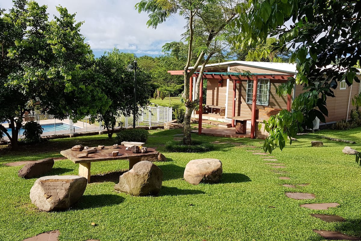 Una casa con piscina, rodeada de exuberante vegetación y senderos de piedra.