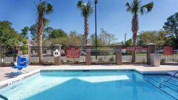 A swimming pool with a lifeguard on duty sign, shallow water diving allowed sign, and a no swimming at your own risk sign.