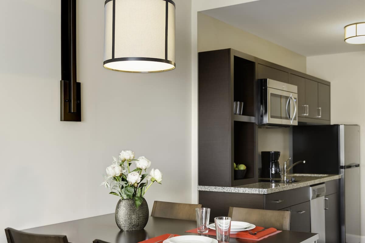 A modern kitchen with dark cabinetry, a microwave, and a refrigerator.