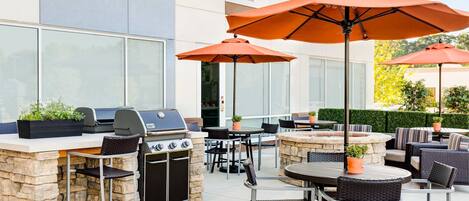 An outdoor patio with stone countertops, a grill, and wicker furniture.