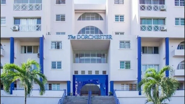 Ein Hotel namens "The Dorchester" mit einem zentralen Eingang, mehreren Etagen und einer Treppe, die zum Eingang führt.