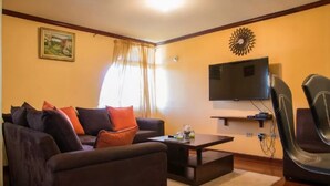 Ein Wohnzimmer mit Sofa, Sessel, Couchtisch, Fernseher und einer Wanddekoration.