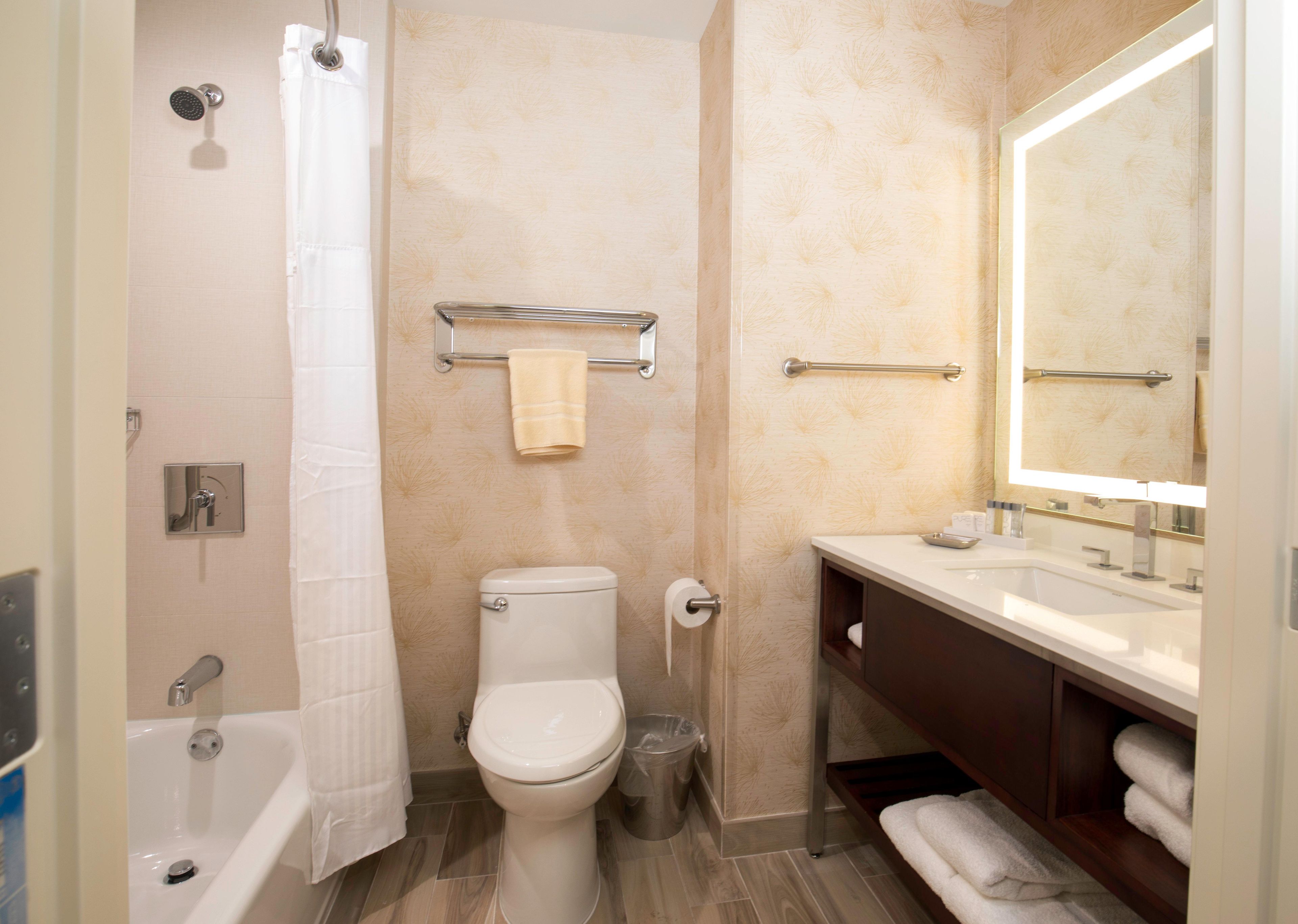 Un baño con bañera, inodoro y tocador con espejo.