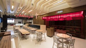 A modern restaurant with a pick-up counter, wooden tables, and chairs. - The Landing Hotel at Rivers Casino Schenectady (Schenectady)
