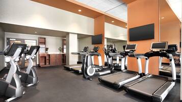 A gym with treadmills, elliptical machines, and a reception desk.