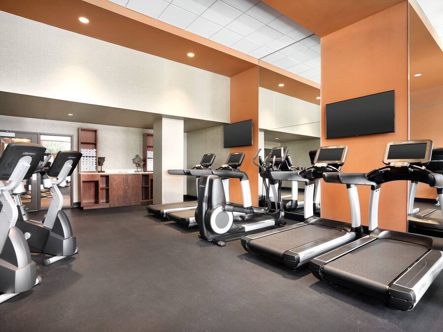 A gym with treadmills, elliptical machines, and a reception desk.