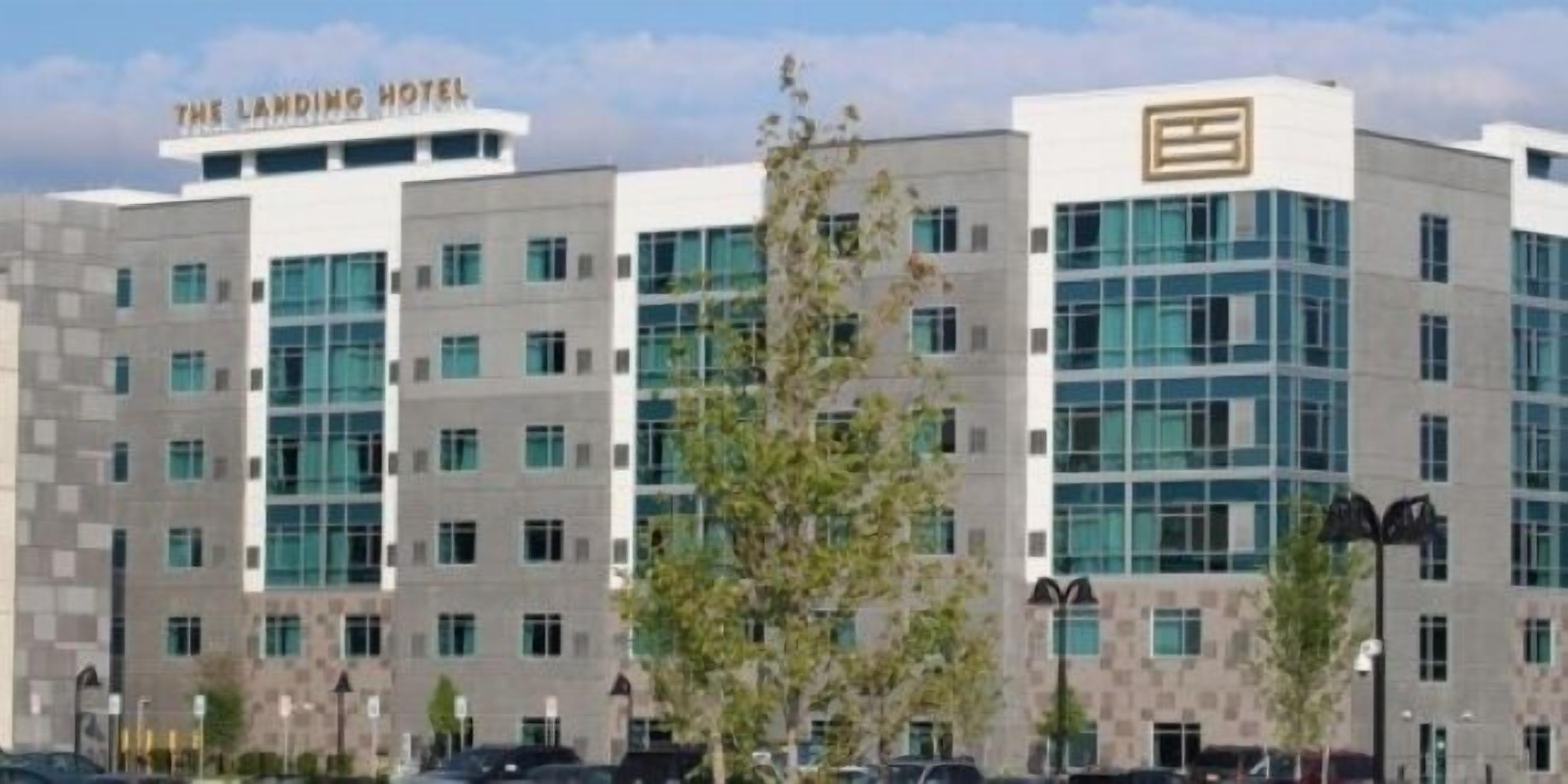 A modern hotel building with multiple floors, large windows, and a prominent sign at the top.