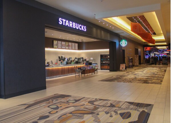 A Starbucks inside a shopping mall with a modern interior design, a counter, and seating area.