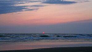 Ein Strand mit Wellen und einem Sonnenuntergang.