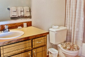A bathroom with a wooden vanity, a sink, a toilet, and a mirror. - Ocean Surf Condos (Ocean Shores)