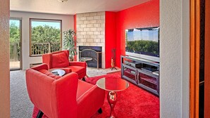 Ein modernes Wohnzimmer mit roten Möbeln, einem Kamin und einem großen Fernseher.