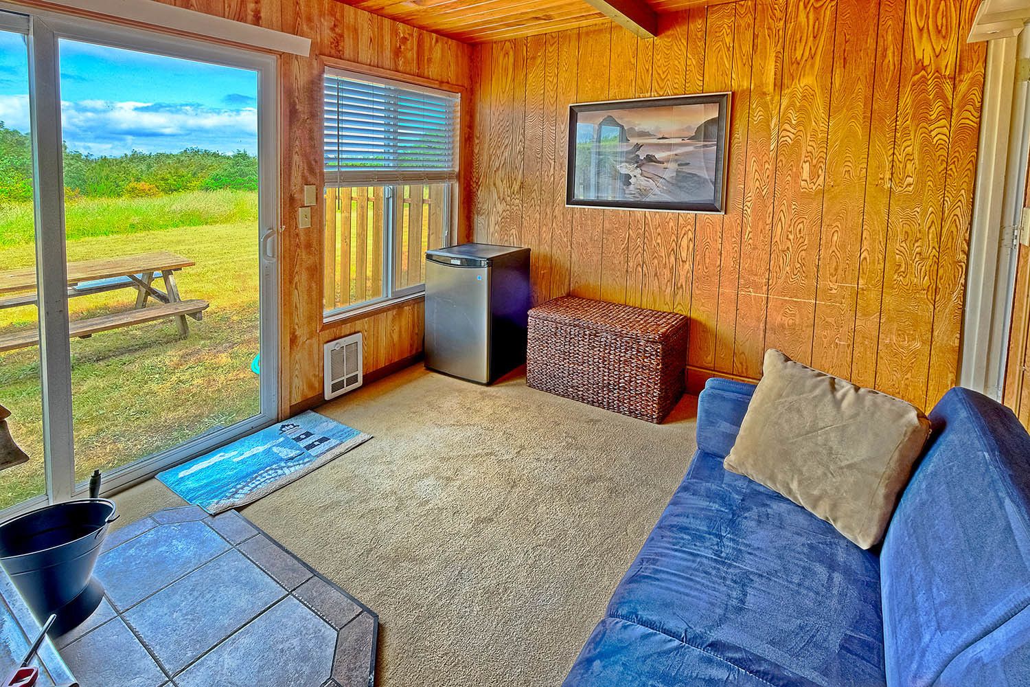 A cozy room with a wooden interior, a blue sofa, a small table, and a picture on the wall.