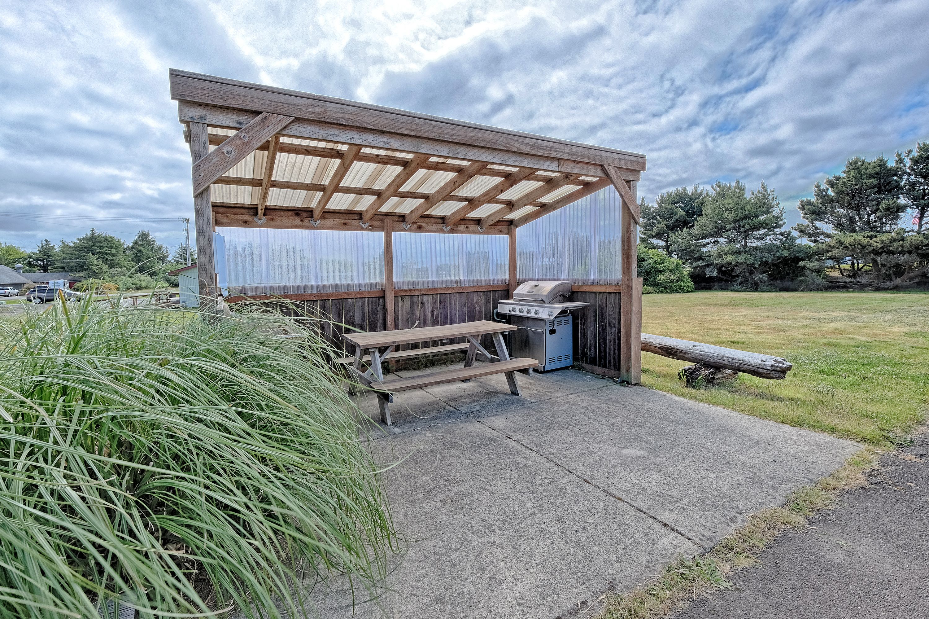 A covered outdoor area with a grill and picnic table.