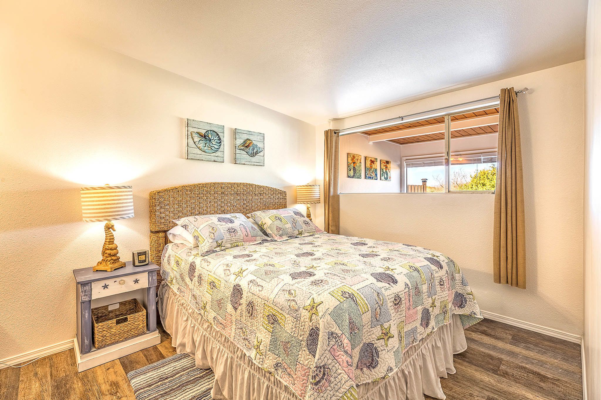 A bedroom with a bed, two wall-mounted lamps, a small side table, and a window with curtains.