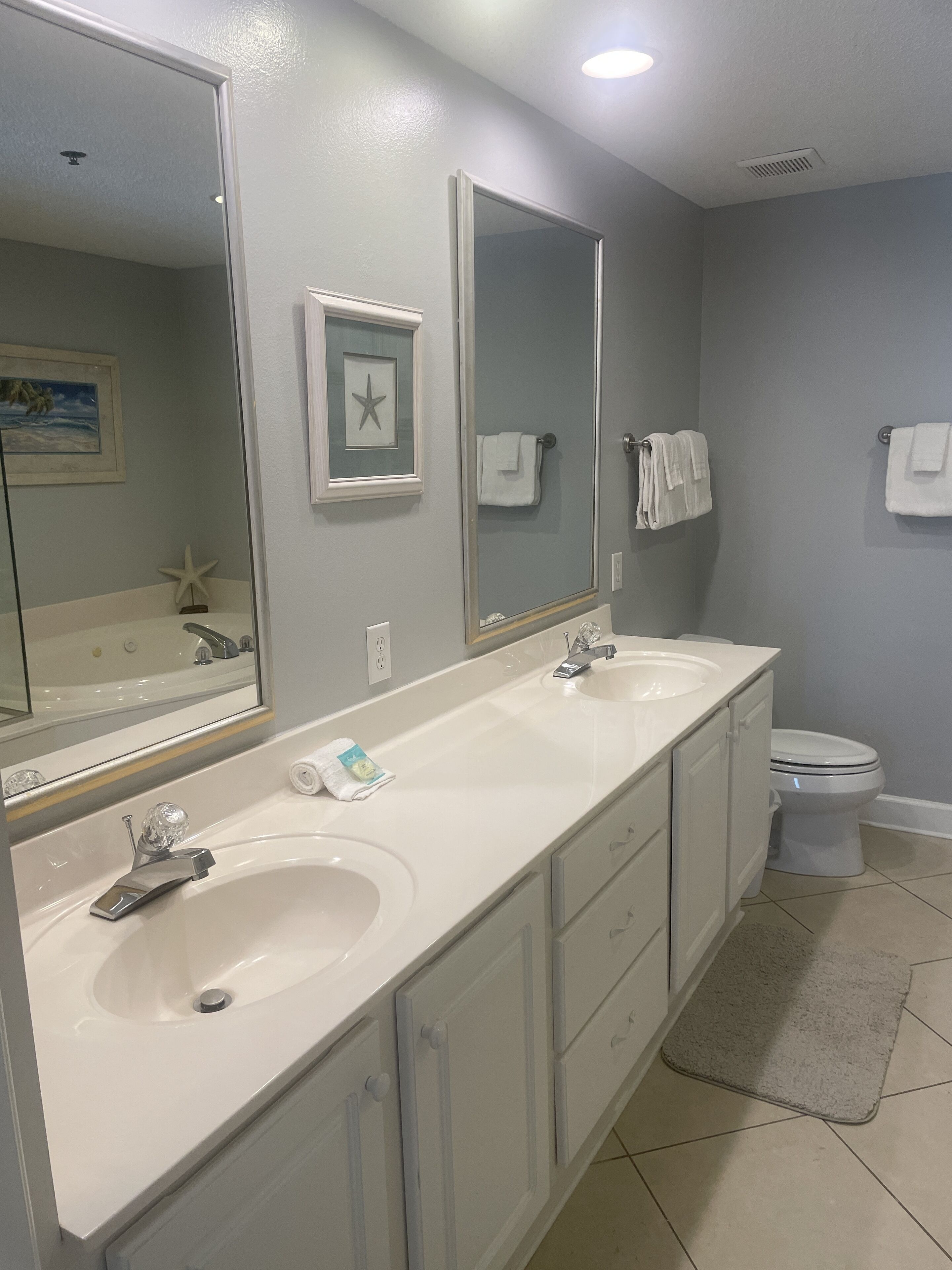 A bathroom with two sinks, a toilet, and a large mirror.