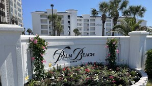 Naamplaatje voor Palm Beach met een decoratieve tuin ervoor.
