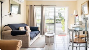 A cozy living room with a sofa, a small round table, and a dining area with chairs.