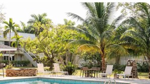 A pool area with lounge chairs and palm trees.