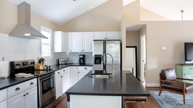A modern kitchen with white cabinets, stainless steel appliances, and a large island with a sink.
