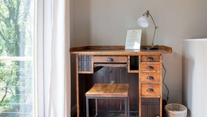A wooden desk with drawers, a small bench, and a desk lamp.