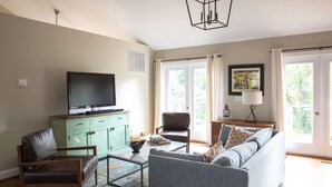 A living room with a television, a sofa, a coffee table, and a bookshelf.