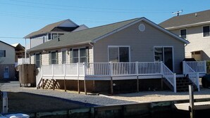 A two-story house with a covered front porch and a small deck. - Charming canal front home, quiet neighborhood, one mile from ocean, Prof. Clean. (Selbyville)