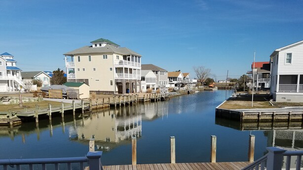 A waterfront property with a dock, a wooden deck, and a view of houses along the water. - Charming canal front home, quiet neighborhood, one mile from ocean, Prof. Clean. (Selbyville)
