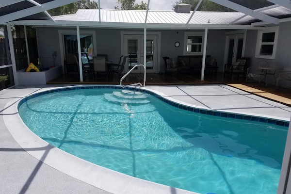 Pool looking to back porch with table to left and large seating area to right