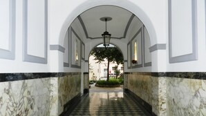 Un pasillo con suelo de tablones, paredes blancas y techo abovedado.