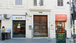 Un edificio con una puerta de madera grande, un escaparate con un letrero y una caja verde con grafitis.