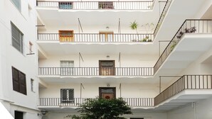 Un edificio de varios pisos con balcones, ventanas y algunas plantas.