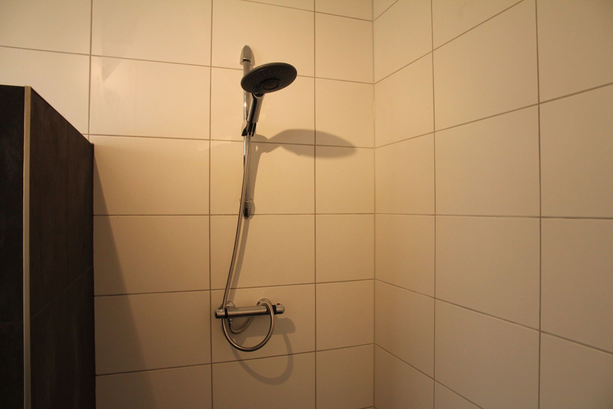 A shower with a handheld showerhead and a handheld hose.