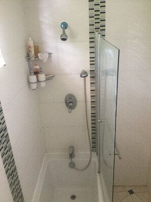 Een bad/douchecombinatie, handdoeken, zeep, toiletpapier