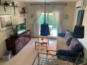 A living room with a television, sofa, and a table with a lamp. - Townhouse for rent in the summer season Estartit (L'ESTARIT)