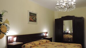 A bedroom with a bed, a nightstand, a dresser, a mirror, and a chandelier. - Isolated on hill, flat with terrace,garden among romanesque art,quiet,nature (cocconato)