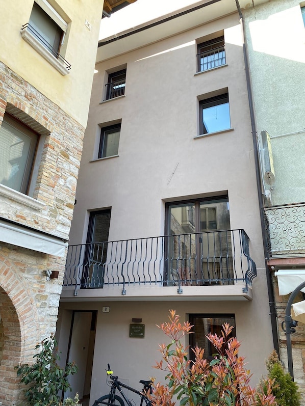 Ein mehrstöckiges Gebäude mit einem Balkon im Erdgeschoss.