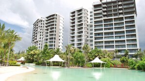 Un hôtel moderne composé de plusieurs immeubles de grande hauteur, doté d’une piscine et agrémenté de palmiers.